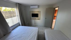 a white bedroom with a bed and a window at Via do Sol flats in Amontada
