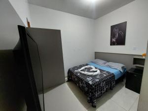 a small bedroom with a bed and a television at Suíte Casal - Queen's Hotel in Formosa