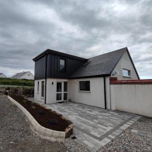 a small white house with a black roof at An Camus Ballyliffin in Ballyliffin