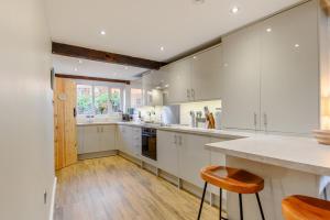 a large kitchen with white cabinets and wooden floors at 4 Bed in Sheringham oc-m28357 in Sheringham