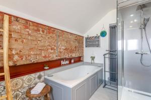 a bathroom with a bath tub next to a brick wall at 3 Bed in Crowle oc-s30617 in Crowle +21 photos
