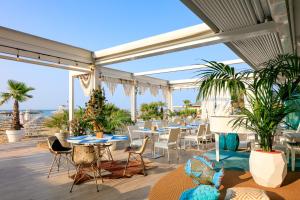 a patio with tables and chairs and palm trees at Hotel Bellariva in Lido di Jesolo