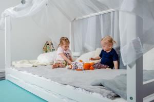 two little girls sitting on a bed at OREA Resort Devět Skal Vysočina in Sněžné