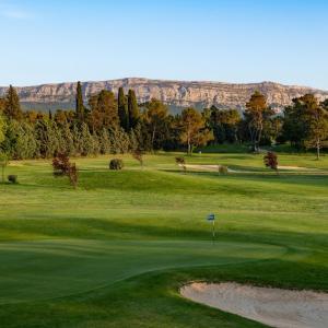 a view of a golf course with mountains in the background at Chez Christine et Marcel in Nans-les-Pins