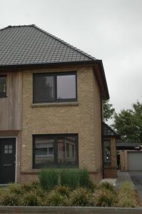 a brown brick house with black windows at Vakantiewoning Duinviooltje-Koksijde in Koksijde