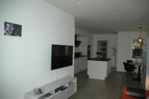 a kitchen and living room with a tv on a wall at Vakantiewoning Duinviooltje-Koksijde in Koksijde