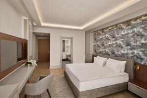 ein Schlafzimmer mit einem großen weißen Bett und einem Schreibtisch in der Unterkunft Concorde Tower Hotel & Casino in Lefkosa Turk