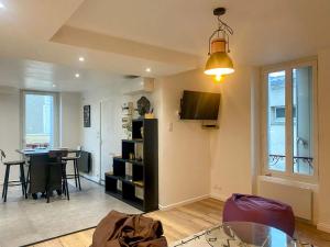 a living room with a table and a tv on the wall at Le Calypso pour 4 pers CLIM CONFORT INTERNET PROCHE DE LA GARE in Marmande