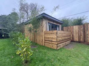 a small wooden shed in a yard next to a fence at Willow Lodge in Ringwood