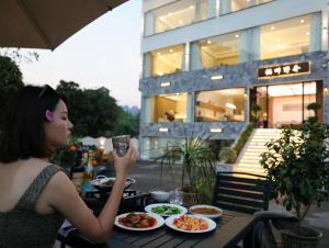 a woman sitting at a table with plates of food at NAIYI Forest Park Resort in Zhangjiajie