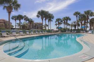 a large swimming pool with chairs and palm trees at Destiny Beach Villas #9A in Destin