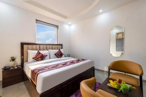 a bedroom with a large bed and a chair at Hotel Park Tree I Sec-63A I Noida I Couple Friendly and Corporate Rooms available in Noida +67 photos