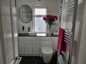 a bathroom with a toilet and a vase of flowers at Shalom, in Saundersfoot, near the sea in Saundersfoot