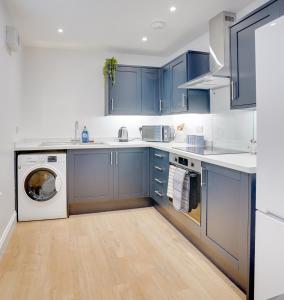 a kitchen with blue cabinets and a washer and dryer at Apt 2 Armatage Flats, Eyemouth in Eyemouth