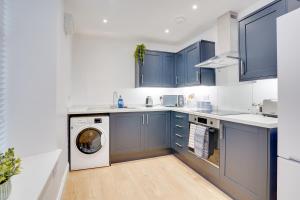 a kitchen with blue cabinets and a washer and dryer at Apt 2 Armatage Flats, Eyemouth in Eyemouth +7 photos