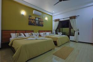 two beds in a room with yellow walls at Canal's Edge in Negombo +118 photos