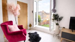 a black dog sitting in a living room with a chair and a window at AMETHYST - 4br all with ensuite & parking in Cambridge