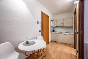 a small kitchen with a white table and white chairs at Emilia Studios 5 in Modena