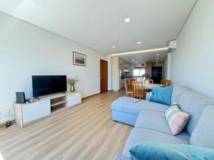 a living room with a blue couch and a television at Refugio do Atlântico in Marinhas