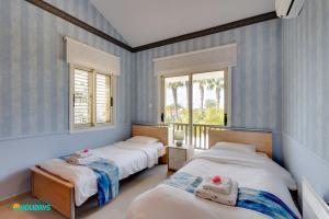 two beds in a room with blue striped walls at Beachfront Villa Carpe Diem in Mor Menekshe