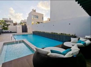 a swimming pool with two lounge chairs next to a building at Casa de lujo en Playa del Carmen in Playa del Carmen