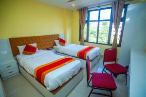 a bedroom with two beds and two red chairs at Hotel Ganga Sagar in Kathmandu