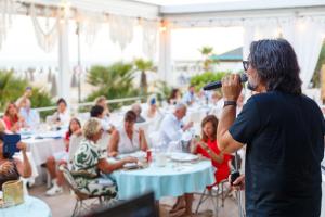 a man singing into a microphone in a restaurant at Hotel Bellariva in Lido di Jesolo +70 photos