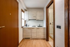 a small kitchen with wooden cabinets and a sink at Emilia Studios 8 in Modena +8 photos