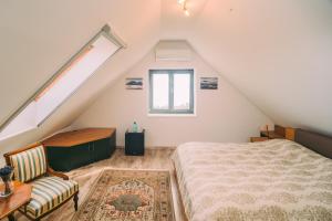 a attic bedroom with a bed and a window at Éliás Borbirtok in Badacsonytomaj