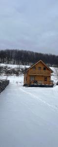 a log cabin in the snow next to a field at Poloniny Osadne in Osadné