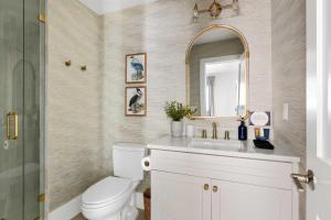 a bathroom with a toilet and a sink and a mirror at The Sumter 1bd Condo 1 Block to Ocean in Folly Beach