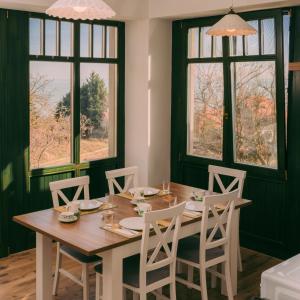 a dining room with a table and chairs and windows at Éliás Borbirtok in Badacsonytomaj