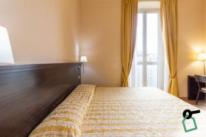 a bedroom with a bed with a wooden headboard and a window at Hotiday Cagliari Lungomare in Cagliari