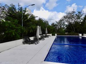 a swimming pool with lounge chairs and umbrellas next to at NEW! Jungle Chic Retreat in Aldea Tulum in Tulum