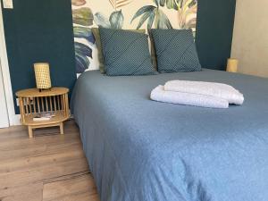 a blue bed with two towels on top of it at La Chambre Bleue in Quimper