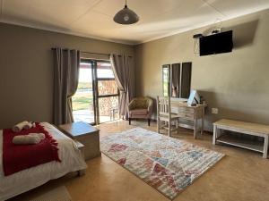 a bedroom with a bed and a desk and a television at Lake Grappa Guestfarm in Augrabies