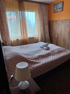 a bedroom with a bed with a lamp and a window at Парк-хотел Родопи in Churen