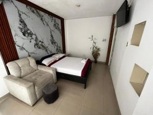 a small bedroom with a bed and a chair at Hostal Casa Blanca in El Coca