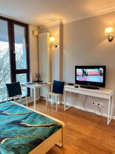 a hotel room with a television and a desk with chairs at HomeComfort Atlantic Room in Warsaw