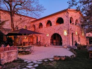 a large brick building with a table and an umbrella at La Flor Azul in Grospierres