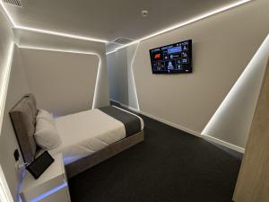 a small room with a bed and a tv on the wall at Futurotel Space Spa Madrid Center in Madrid