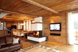 a living room with a fireplace and a television at Maierl-Alm & Maierl-Chalets in Kirchberg in Tirol