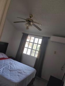 a bedroom with a ceiling fan and a window at Casa Ixtapa in Ixtapa