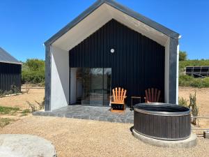 ein schwarzes Gebäude mit zwei Stühlen und einem Fass in der Unterkunft Riverview Rest in Addo