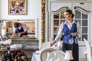 a woman standing in a kitchen with a table at Boutique Hotel Postgården in Holsted