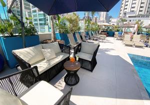 a patio with chairs and an umbrella and a pool at Hotel Sibara SPA & Convenções in Balneário Camboriú