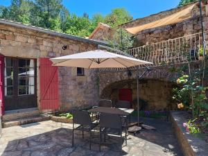 a table with an umbrella in front of a building at Aqua Terra Silva in Gravières