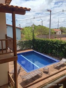 a small swimming pool on a wooden deck with chairs at pousada mar e vento in Touros