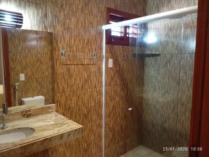 a bathroom with a glass shower and a sink at pousada mar e vento in Touros