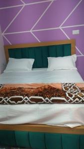 a bedroom with a bed with a purple wall at Hotel Dharma palace in Prayagraj